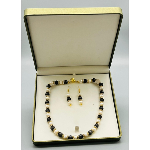 85 - A very feminine, genuine pearl and cat’s eyes necklace and earring set, with cubic zirconia. In a pr... 