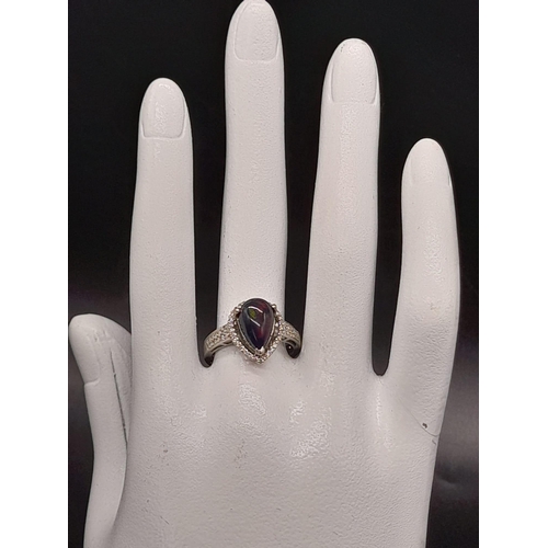 751 - A Stunning 18K White Gold Black Opal and Diamond Ring. Teardrop shaped black opal surrounded by a te... 