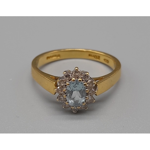 759 - An 18K Yellow Gold, Aquamarine and Diamond Ring. Central aquamarine stone surrounded with a halo of ... 