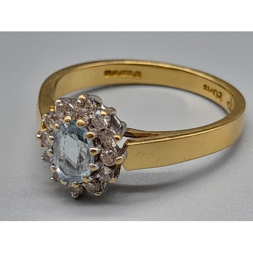 759 - An 18K Yellow Gold, Aquamarine and Diamond Ring. Central aquamarine stone surrounded with a halo of ... 