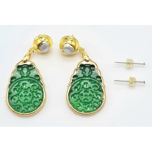 133 - An intricately carved green jade pair of earrings with genuine pearls. Length: 6 cm. Presented in a ... 