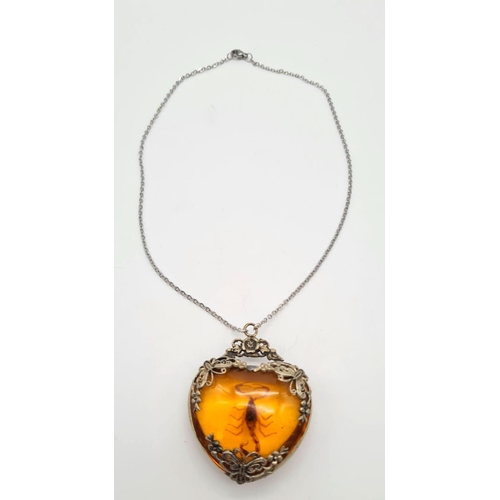 238 - A vintage, heart shaped, amber pendant with a small scorpion inclusion, on a sterling silver chain. ... 