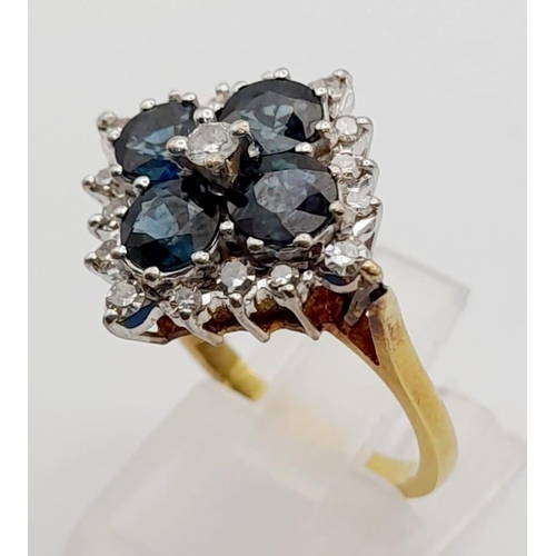 453 - An 18K Yellow Gold Diamond and Sapphire Ring. Four clean blue sapphires surrounded by a cluster of d... 