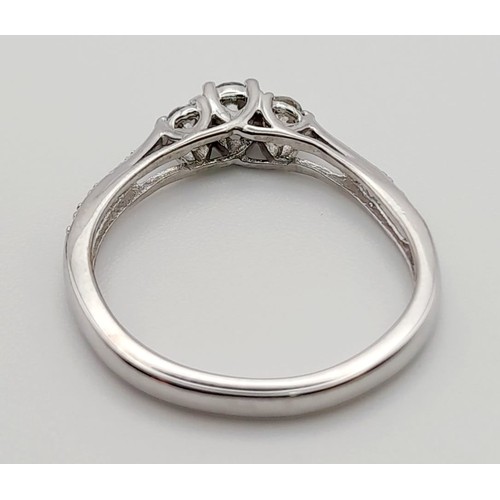 587 - A 9K White Gold Three Diamond Stone Ring. Size M.
1.9g. Plus smaller diamonds on shoulders.