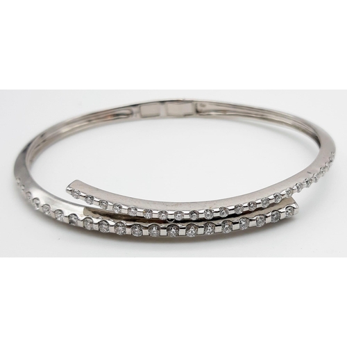 443 - A 14K WHITE GOLD AND DIAMOND BANGLE IN STUNNING CROSS-OVER MODERN DESIGN WITH 2CT DIAMONDS . 16.2gms