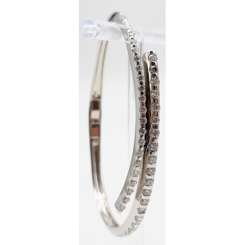 443 - A 14K WHITE GOLD AND DIAMOND BANGLE IN STUNNING CROSS-OVER MODERN DESIGN WITH 2CT DIAMONDS . 16.2gms