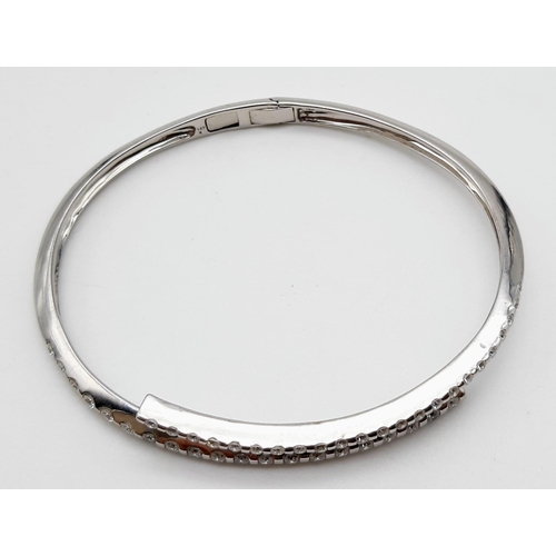 443 - A 14K WHITE GOLD AND DIAMOND BANGLE IN STUNNING CROSS-OVER MODERN DESIGN WITH 2CT DIAMONDS . 16.2gms