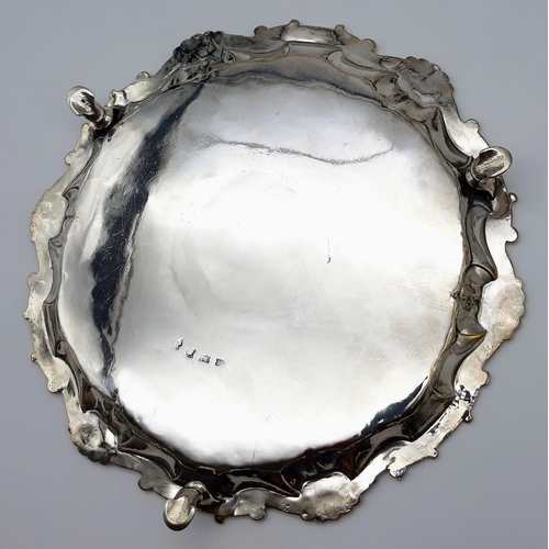 485 - A HALLMARKED SILVER FOOTED PLATTER DATED 1745 WITH SHELL AND SCROLL EDGING. 452gms   24cms diameter