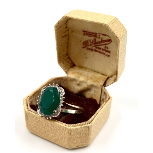 225 - A LARGE VINTAGE EMERALD RING SET IN 18K WHITE GOLD WITH A DIAMOND HALO. 3.5gms   size U