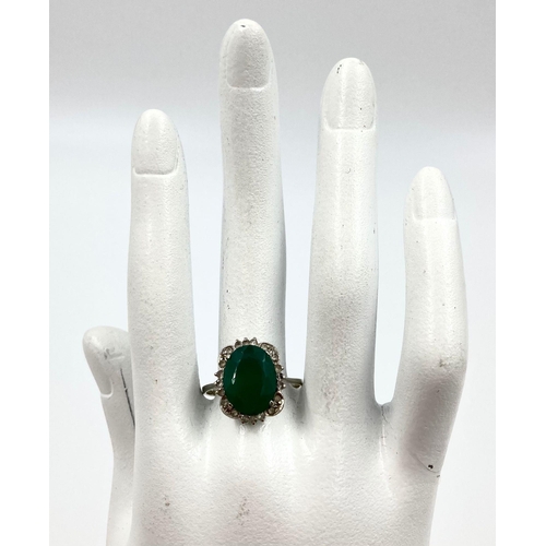 225 - A LARGE VINTAGE EMERALD RING SET IN 18K WHITE GOLD WITH A DIAMOND HALO. 3.5gms   size U