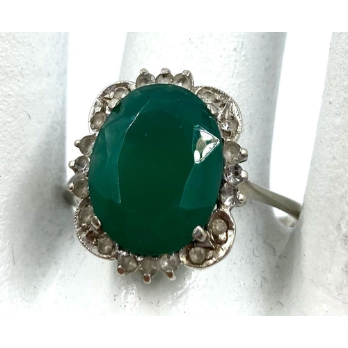 225 - A LARGE VINTAGE EMERALD RING SET IN 18K WHITE GOLD WITH A DIAMOND HALO. 3.5gms   size U