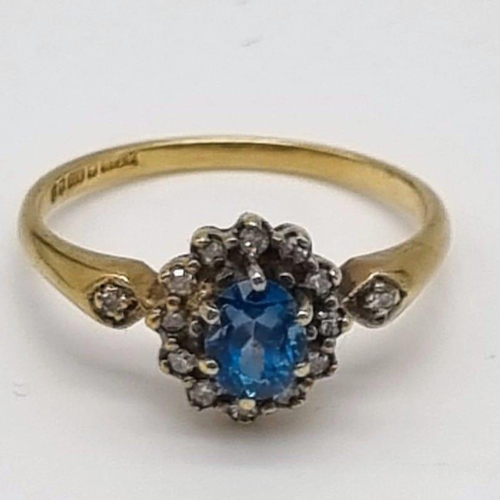 53 - A 9K Yellow Gold Topaz and Diamond Ring. Centre blue topaz surrounded by a halo of diamonds. Size L.... 