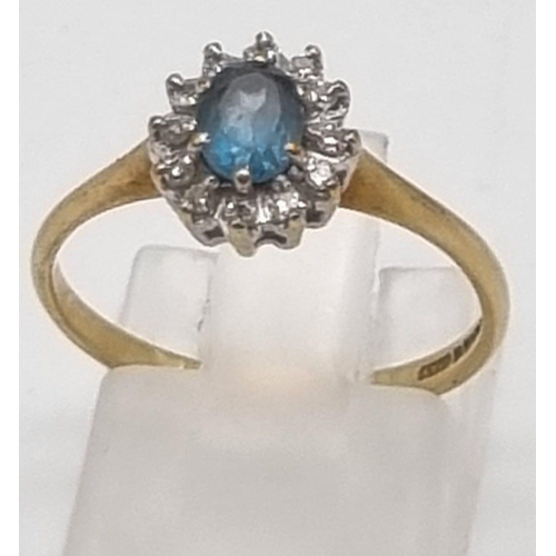 509 - A 9K Yellow Gold Topaz and Diamond Ring. Centre blue topaz surrounded by a halo of diamonds. Size L.... 