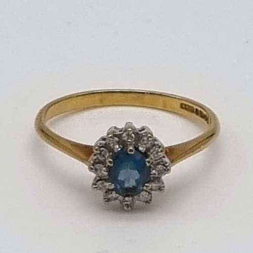 509 - A 9K Yellow Gold Topaz and Diamond Ring. Centre blue topaz surrounded by a halo of diamonds. Size L.... 