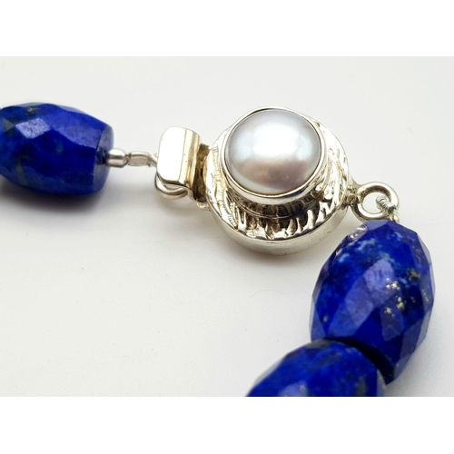 634 - A 495ct Fancy Lapis Lazuli Drum Shape bead necklace with a Pearl clasp in 925 silver. 44cm.