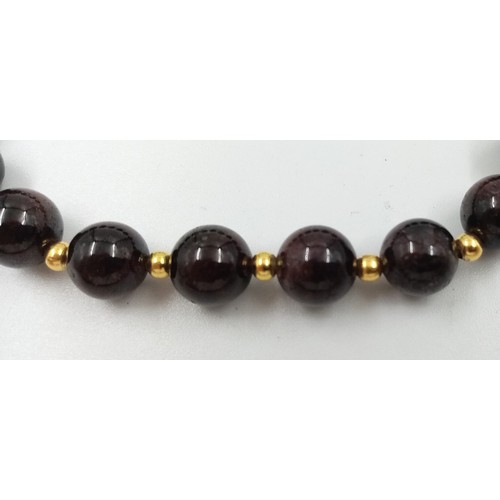 886 - An Expandable Garnet Bead Bracelet with Gilded Spacers.