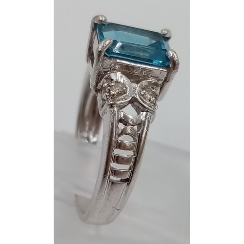 405 - A 9K White Gold Topaz and Diamond Ring. Emerald cut bright topaz with two diamonds either side. Size... 