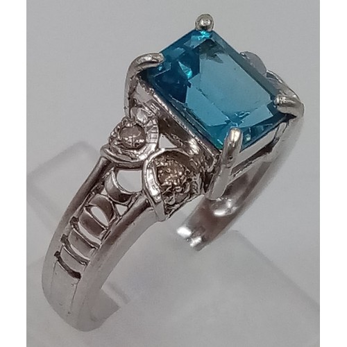 405 - A 9K White Gold Topaz and Diamond Ring. Emerald cut bright topaz with two diamonds either side. Size... 