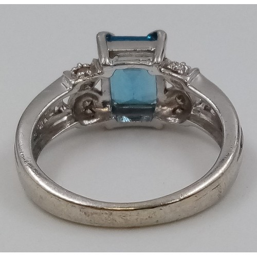 405 - A 9K White Gold Topaz and Diamond Ring. Emerald cut bright topaz with two diamonds either side. Size... 