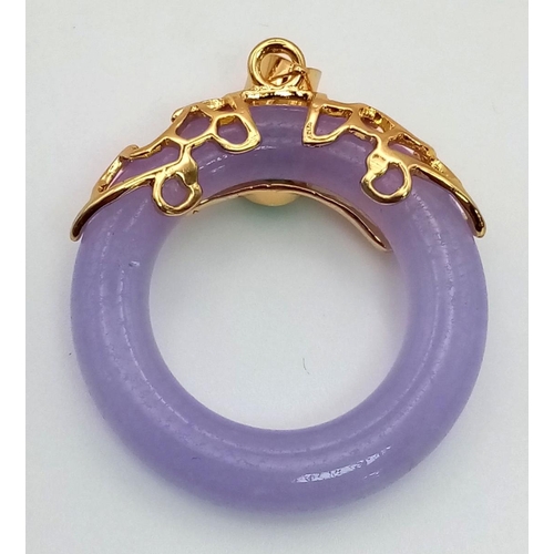 943 - A Lavender Jade Dough Nut Pendant in a Gilded Setting.
3cm.