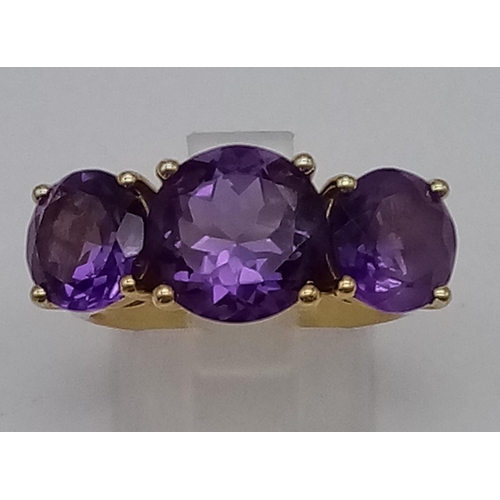 469 - An 18K Yellow Gold and Large Three-Stone Amethyst and Diamond Ring. Three central intense clean amet... 