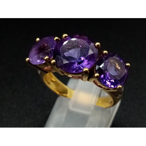 469 - An 18K Yellow Gold and Large Three-Stone Amethyst and Diamond Ring. Three central intense clean amet... 