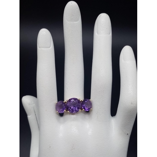 469 - An 18K Yellow Gold and Large Three-Stone Amethyst and Diamond Ring. Three central intense clean amet... 