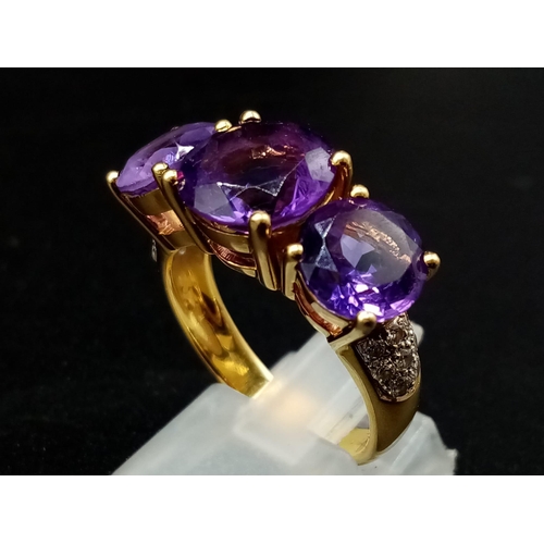 469 - An 18K Yellow Gold and Large Three-Stone Amethyst and Diamond Ring. Three central intense clean amet... 