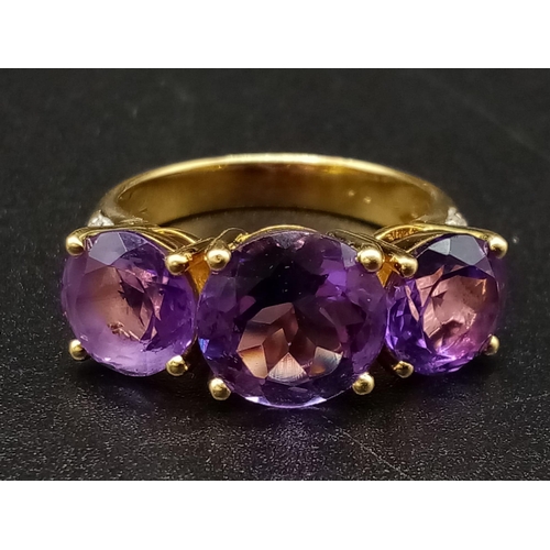 469 - An 18K Yellow Gold and Large Three-Stone Amethyst and Diamond Ring. Three central intense clean amet... 