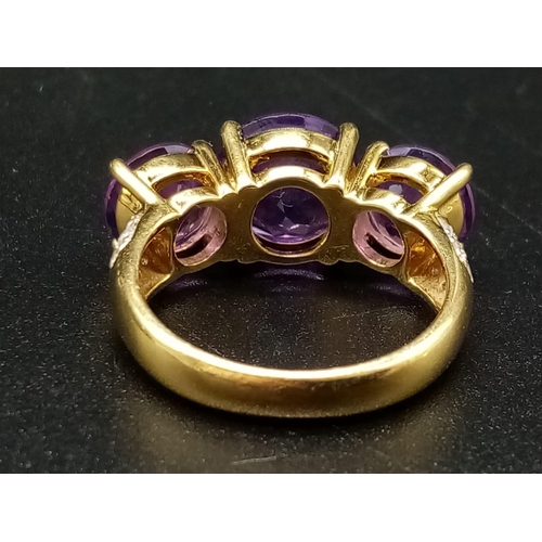 469 - An 18K Yellow Gold and Large Three-Stone Amethyst and Diamond Ring. Three central intense clean amet... 