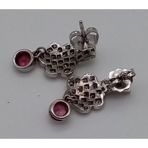 476 - A Pair of 18K White Gold Diamond and Ruby Floral Design Earrings. Diamond cluster with a hanging rub... 