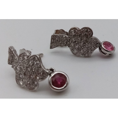 476 - A Pair of 18K White Gold Diamond and Ruby Floral Design Earrings. Diamond cluster with a hanging rub... 