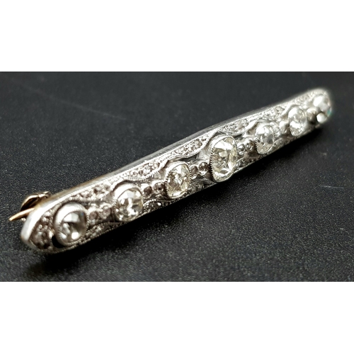 810 - An Antique Platinum and 18K Gold Diamond Bar Brooch. 
Large central round-cut diamond flanked by thr... 