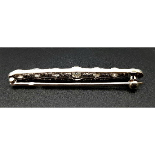 810 - An Antique Platinum and 18K Gold Diamond Bar Brooch. 
Large central round-cut diamond flanked by thr... 