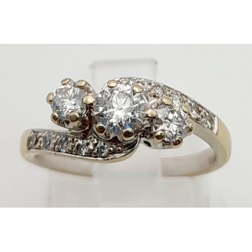 1017 - An 18K Yellow Gold Three-Stone Diamond Crossover Ring. Three central diamonds supported by waves of ... 