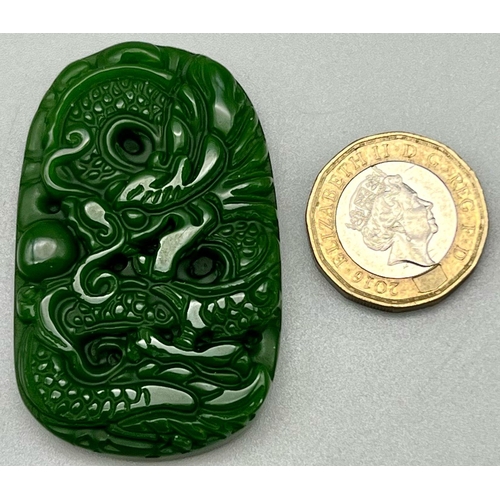 441 - A Carved Dragon Decorated Green Jade Pendant. 3.5 x 5cm.