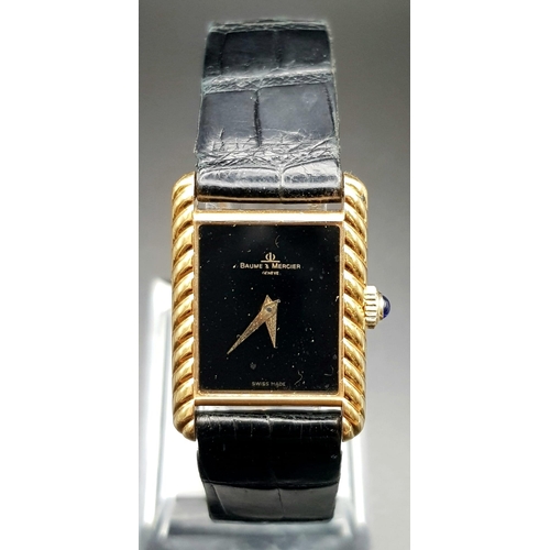 598 - An 18 K yellow gold, ladies, BAUME & MERCIER watch. 20 mm dial, black face with gold hands, sapphire... 