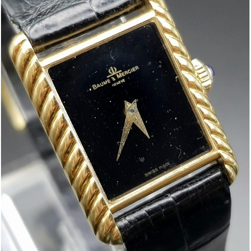 598 - An 18 K yellow gold, ladies, BAUME & MERCIER watch. 20 mm dial, black face with gold hands, sapphire... 