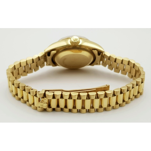 667 - An 18 k yellow gold, ladies, ROLEX DATEJUST watch. 26 mm dial, black face with gold hands and hour m... 