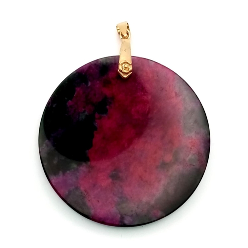 719 - A Red and Black Jade Circular Pendant on Gilded Attachment. 5.5cm diameter.