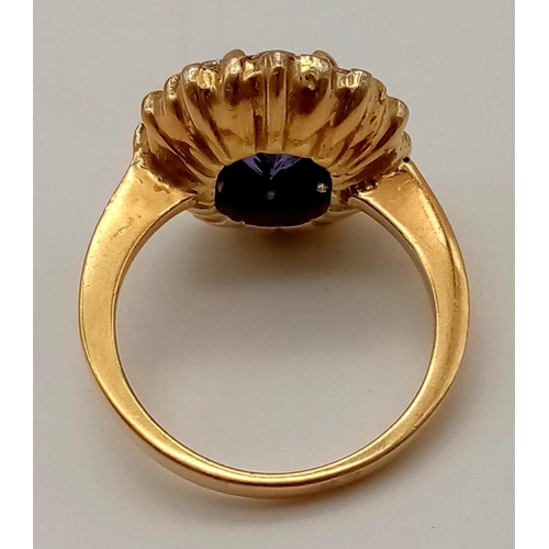 120 - A vintage gold ring with a central oval cut amethyst surrounded by a halo of rose cut diamonds. Ring... 