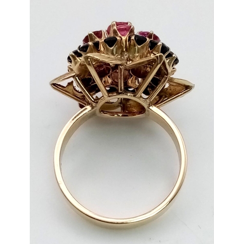 319 - A Vintage 18K Ruby and Sapphire Cluster Ring. Six central rubies with a halo of twelve sapphires. Si... 