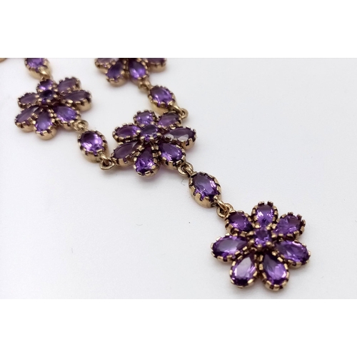 713 - A 9K Yellow Gold and Amethyst Necklace. Amethyst floral decoration and drop pendant. 44cm.  9.59g to... 