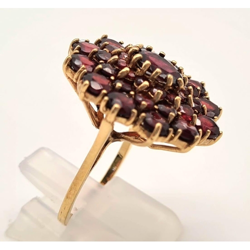 167 - 9K YELLOW GOLD GARNET CLUSTER RING. 7.1G. SIZE L