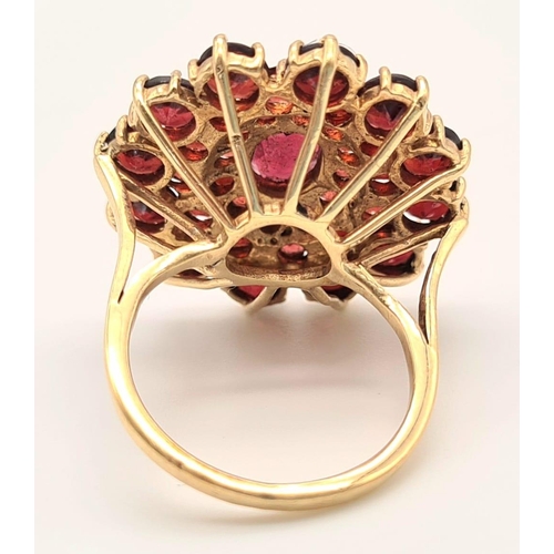 167 - 9K YELLOW GOLD GARNET CLUSTER RING. 7.1G. SIZE L