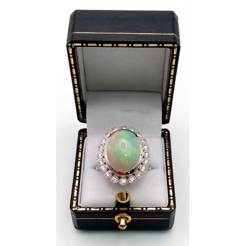 33 - An 18K white gold ring with a large cabochon natural opal (est 6-7 carats) surrounded by a halo of b... 