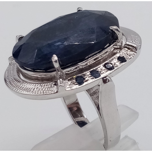 432 - A sterling silver ring with a large oval cut blue sapphire surrounded by a silver halo with eight sm... 