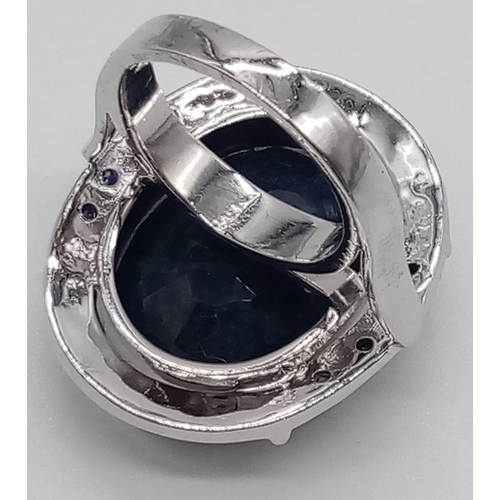 432 - A sterling silver ring with a large oval cut blue sapphire surrounded by a silver halo with eight sm... 