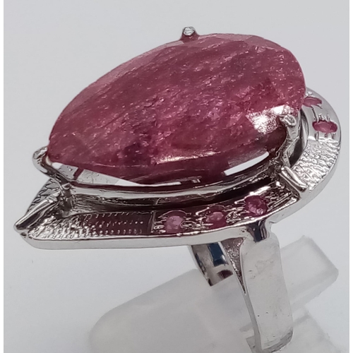 439 - A sterling silver ring with a large pear cut ruby surrounded by a silver halo with nine small rubies... 