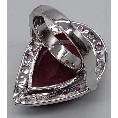 439 - A sterling silver ring with a large pear cut ruby surrounded by a silver halo with nine small rubies... 